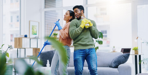 Happy couple, dancing and singing while cleaning living room together for fun disinfection or...