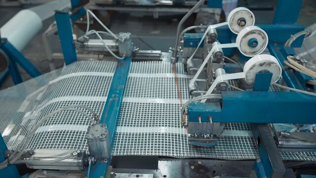 Automated Polymer Mesh Machine. Creative. Machines laying heating wires on polymer grid. Industrial production of modules for floor heating