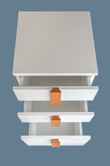 Stylish white office commode with wooden handles and legs with open empty drawers isolated on blue background. Comfortable furniture for home and office furnishing
