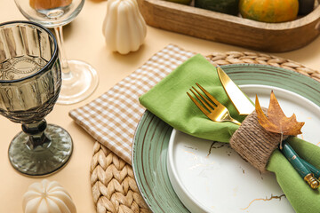 Stylish table setting with autumn leaf on beige background