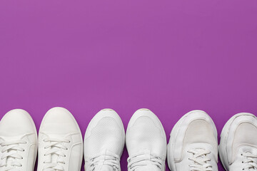 Stylish white sneakers on purple background