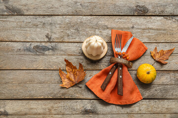 Autumn table serving with cutlery in folded napkin and pumpkins on grey wooden table