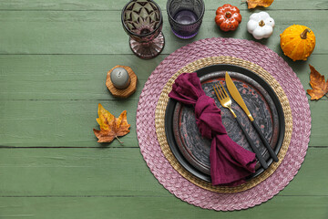 Autumn table serving with golden cutlery and pumpkins on green wooden table