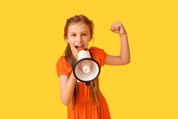 Little girl with megaphone showing muscles on yellow background