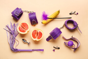 Different sex toys and tasty fruits on beige background