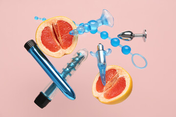 Flying sex toys and tasty grapefruit on beige background