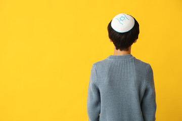 Little Israeli boy in kipa on yellow background, back view
