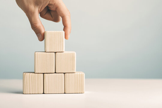 Hand putting and stacking blank wooden cubes on table with copy space for input wording or infographic icon