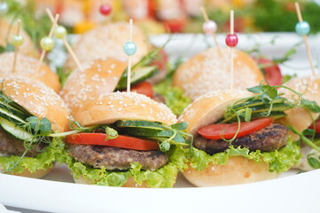 Mini burgers are laid out on a plate.