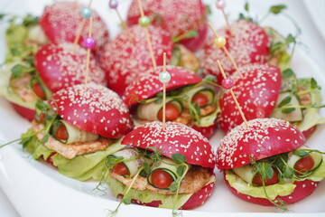 Mini burgers are laid out on a plate.