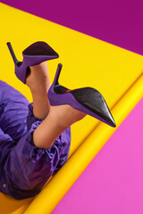 Woman in stylish high heeled shoes lying on color background, closeup