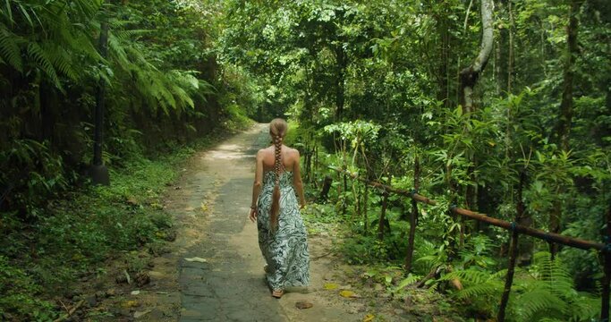 Woman tourist walking in jungle near Tembeling beach and forest in Bali, Nusa Penida, Indonesia. Tropical nature landscape in summer.