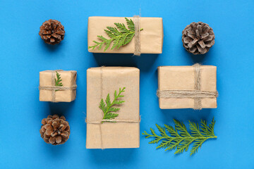 Pine cones with coniferous branches and Christmas gift boxes on blue background