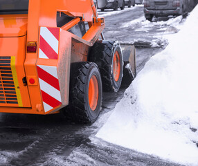 A small orange snowplow removes melted snow from the driveway