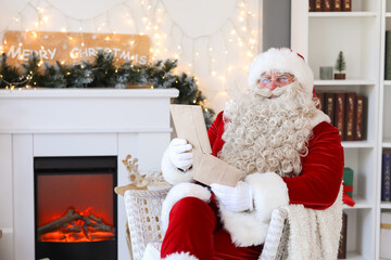 Fototapeta premium Santa Claus with letters at home on Christmas eve