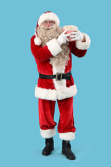 Santa Claus with tasty popcorn on blue background