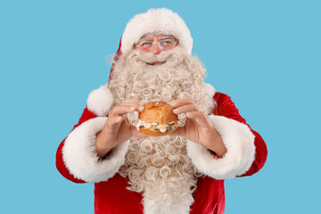 Santa Claus with tasty burger on blue background