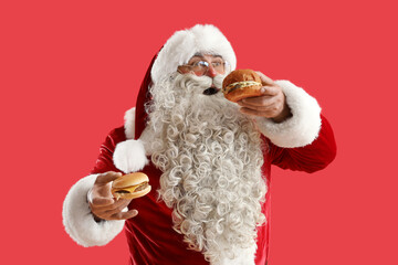 Santa Claus with tasty burgers on red background - obrazy, fototapety, plakaty
