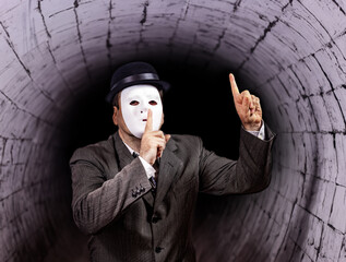 A man in a mask shows a gesture for silence before the enter of the tunnel