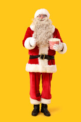 Fototapeta na wymiar Santa Claus with tasty popcorn showing thumb-up on yellow background