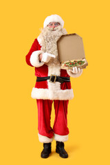 Santa Claus pointing at box with tasty pizza on yellow background