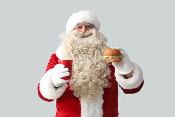 Santa Claus with cup of tea and tasty burger on white background
