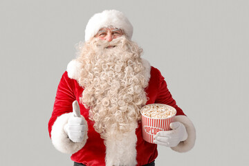Santa Claus with tasty popcorn showing thumb-up on white background