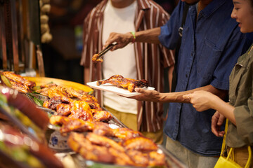 Young people buying fried chicken at street food market