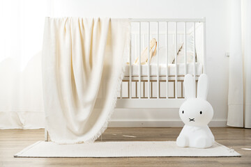 Baby wooden crib and toy rabbit in nursery room