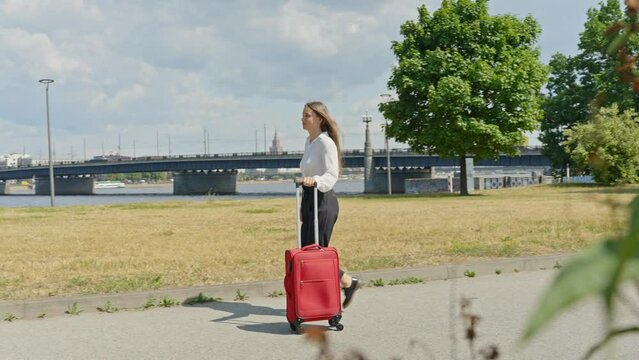 Young entrepreneur female travel to new city with red luggage, follow view