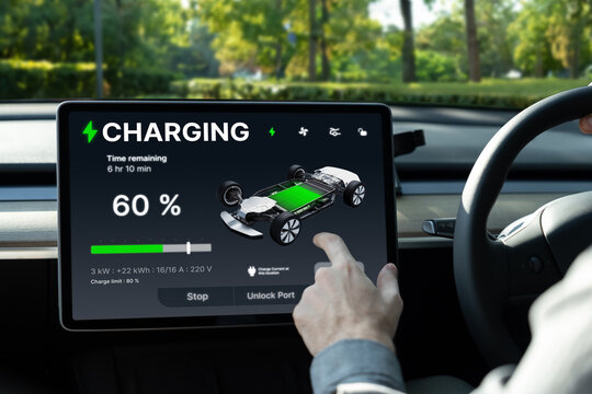 Electric car driver checks battery charging status, range and charging limit on app screen in the car. Smart technology device show EV car recharging data of electric storage in car battery innards.