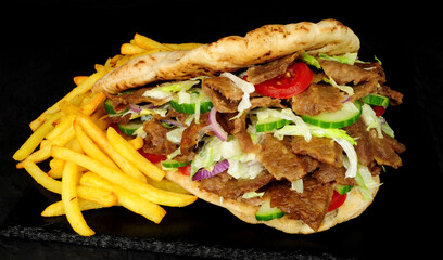 Doner kebab meat and French fries in a naan bread with salad