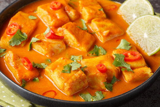 Asian spicy coconut tomato fish curry closeup on a plate on the table. Horizontal