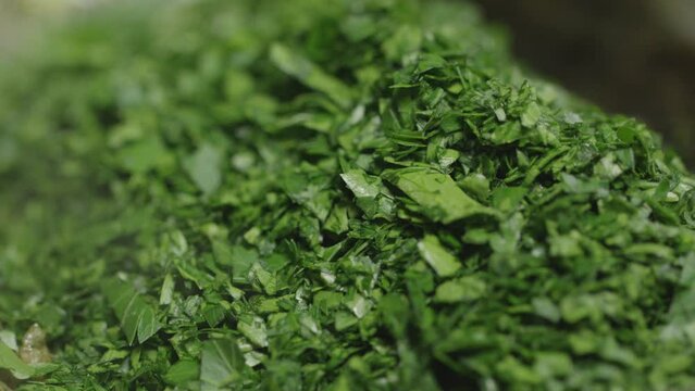 Chopped parsley is placed in a pan. Close up of preparing a delicious cafe de paris sauce.