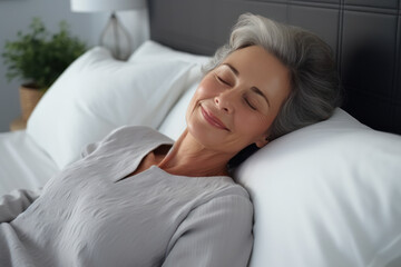 Senior brunette woman sleeping well on white pillow in bed - obrazy, fototapety, plakaty