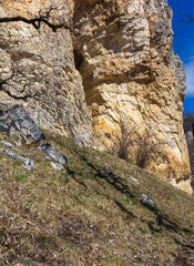 Natural stone walls are the entrance to a cave on a steep cliff of a mountain canyon, walking under rocks.