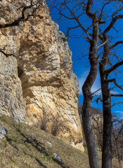 Natural stone walls are the entrance to a cave on a steep cliff of a mountain canyon, walking under rocks.