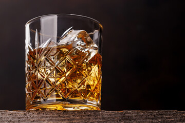 Whiskey glass with ice on a rustic barrel, a classic sip