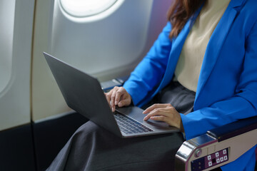 Asian businesswoman uses laptop computer in airplane business travel Online communication and media...