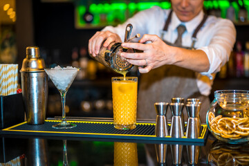 Bartender preparing a cocktail with orange juice