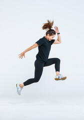 Isolated cutout full body studio shot strong Asian female fitness athlete sportswoman trainer model in casual sport workout outfit posing jumping high in air exercising training on white background