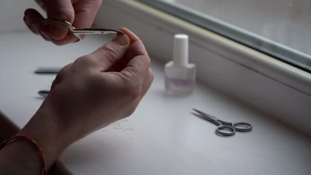 Man's fingers and nails during manicure. Nail sawing with nail file, close up.