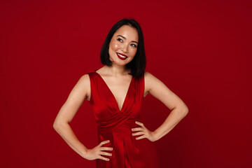 Beautiful asian woman smiling while standing isolated over red background