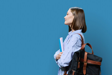 Profile view of young woman college student on blue background