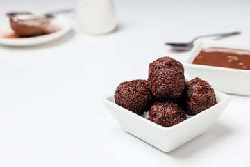 Brigadeiro and chocolate in bowls on white background, space for text