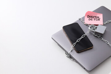 The laptop and smartphone are wrapped in a chain with a lock