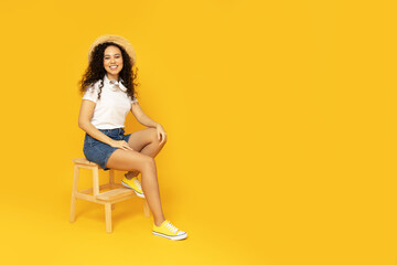 Young attractive girl in a hat on a yellow background