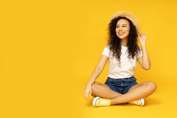 Young attractive girl in a hat on a yellow background