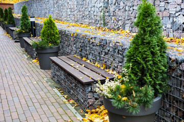 gabion retaining walls. wooden benches built into a dry wall in the park - obrazy, fototapety, plakaty