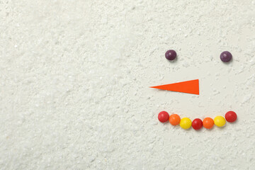 The face of a snowman with paper carrots and candies